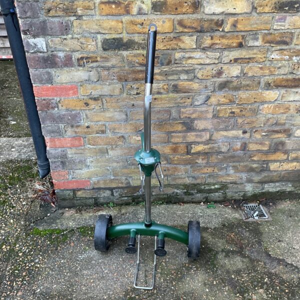 Green metal plant pot trolley in a garden setting.