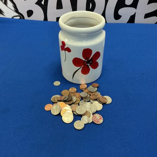 Vintage ceramic jug with poppy design and coins nearby.