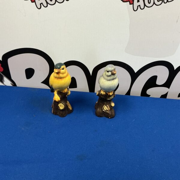 Vintage porcelain bird figurines perched on branches, detailed bird decor.