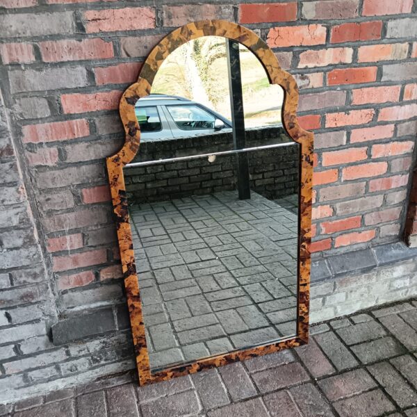 Full view of a Ralph Lauren tortoise shell mirror against a brick wall.