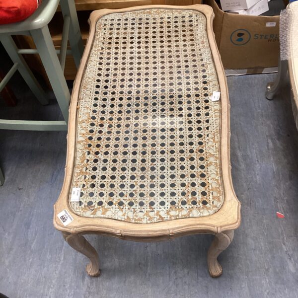 Vintage rattan coffee table with glass top and wooden frame.