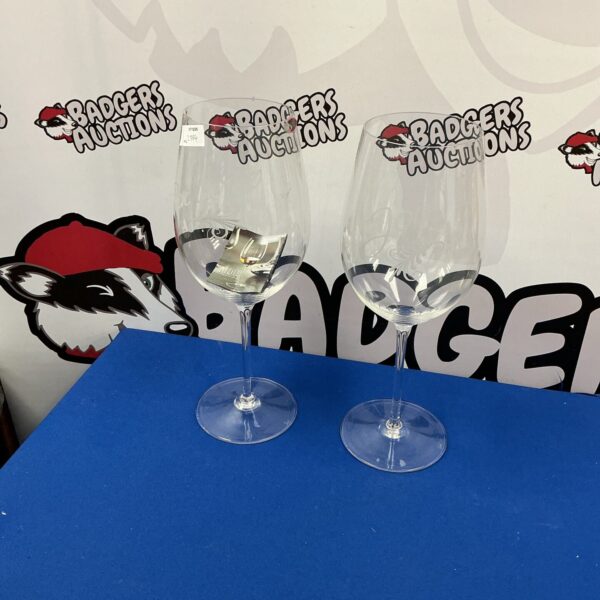 Pair of tall Riedel wine glasses on a neutral background.
