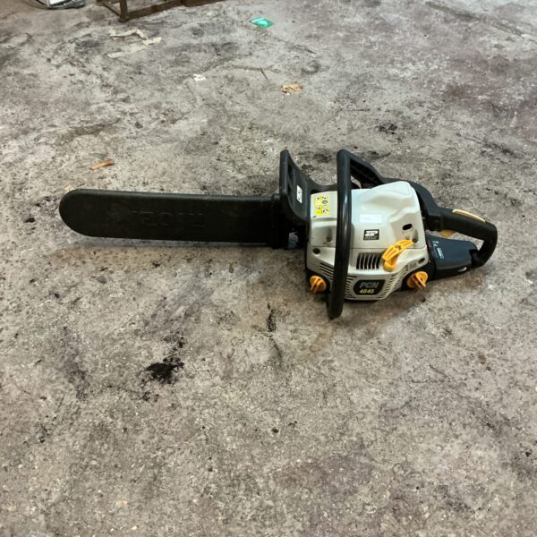 Side view of a used Ryobi petrol chainsaw for garden work.
