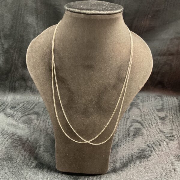 Pair of delicate silver chain necklaces on display.