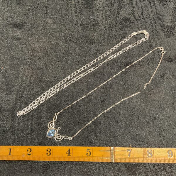 Silver chain necklace with a vibrant topaz pendant, broken chain.