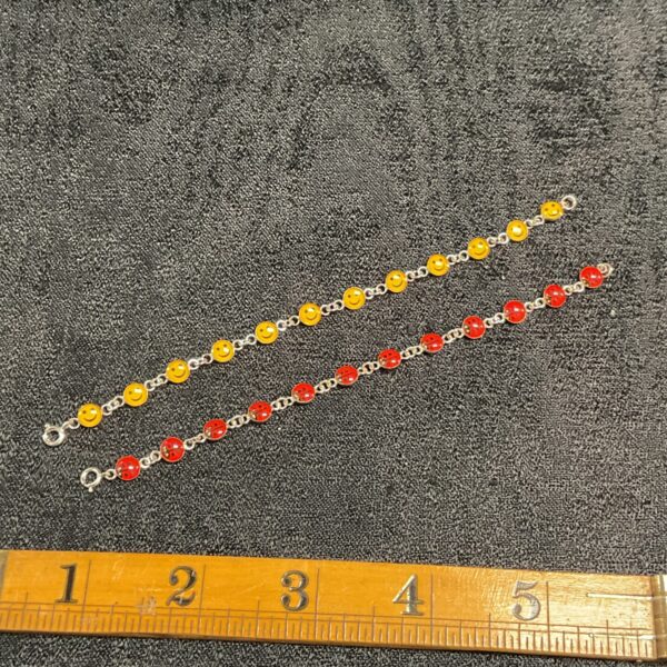 Silver childs bracelets featuring a smiley face and ladybird charms.