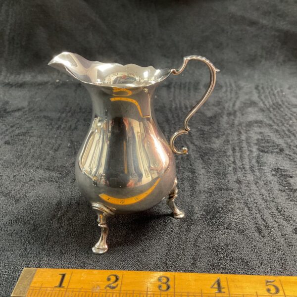 Hallmarked silver cream jug on a ruler for scale.