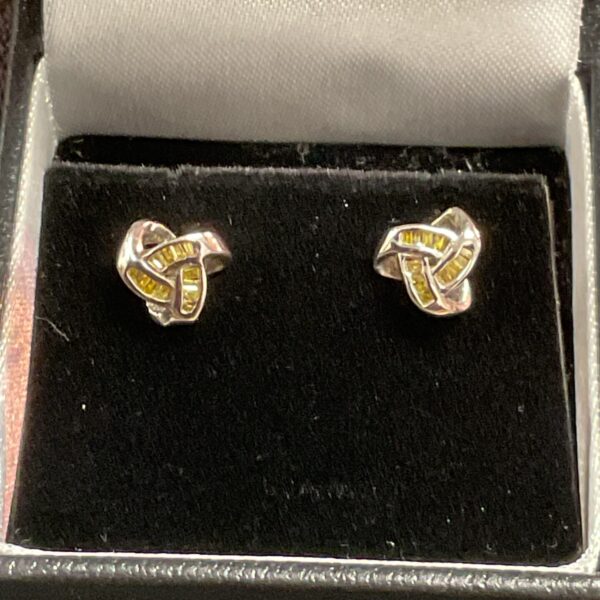 Close-up of silver and diamond stud earrings with textured design.