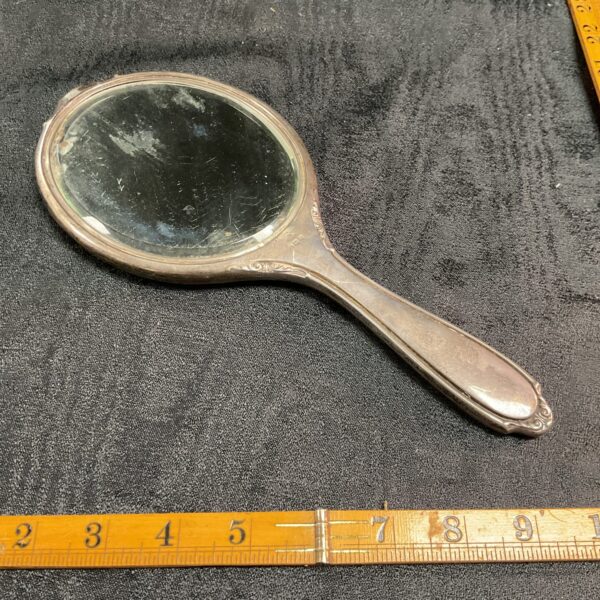 Antique silver hand mirror with embossed handle.