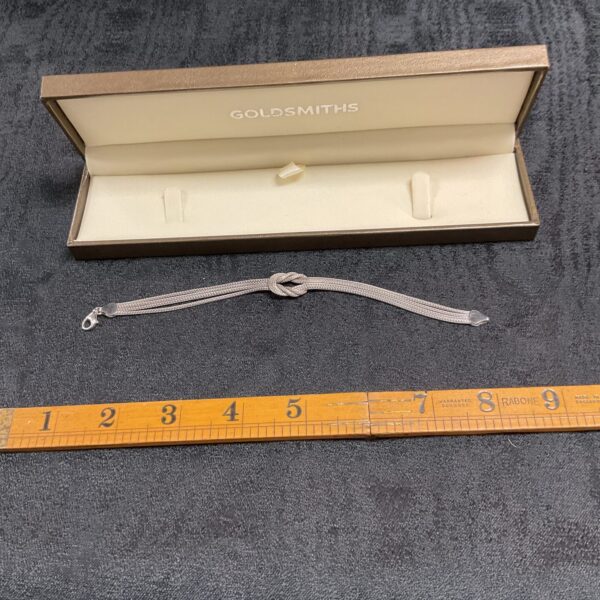 Close-up of a silver knot bracelet, showcasing the detailed design.