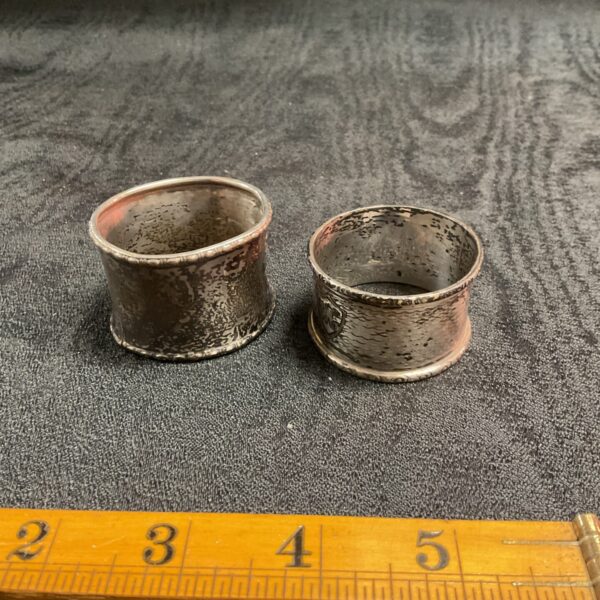 Pair of vintage silver napkin rings on a grey surface.