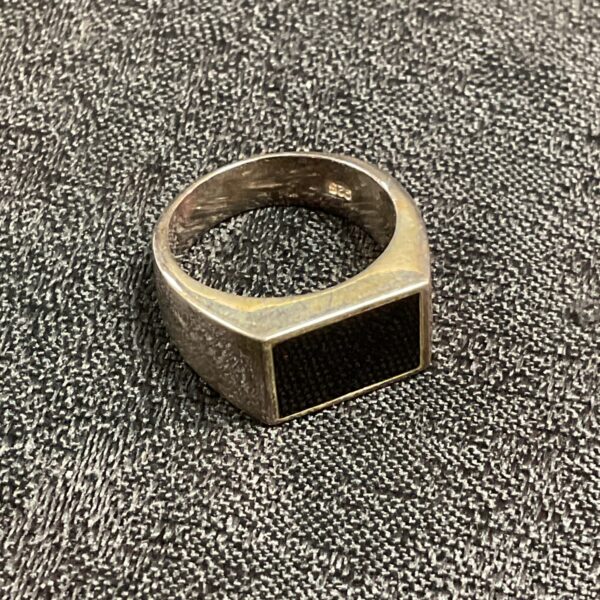 Close-up of a silver ring with a black onyx stone.