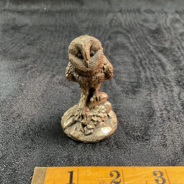 Antique silver owl figurine on dark background.