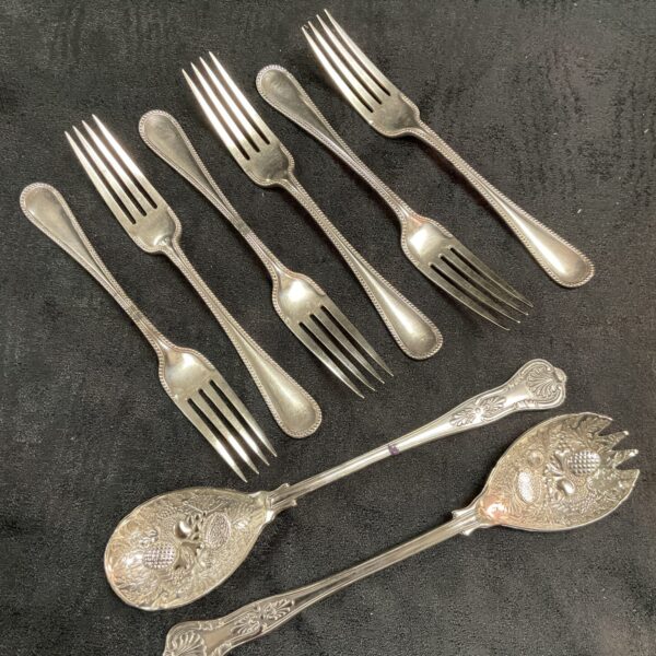 Vintage silver plate berry spoons and beaded forks set on display.