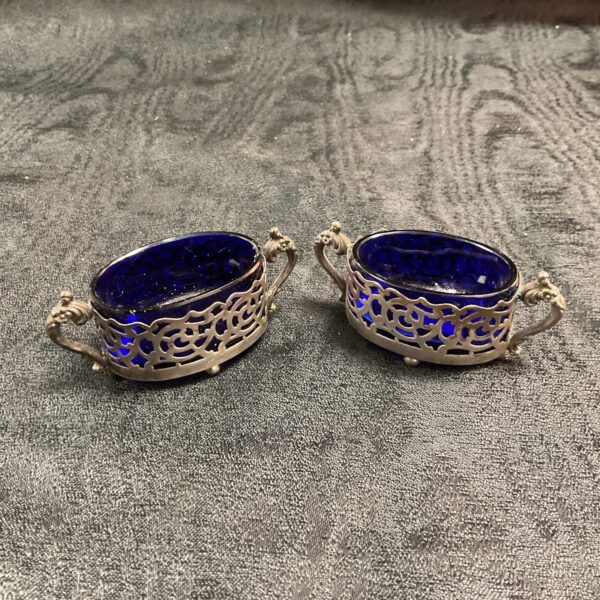 Antique silver salt cellars with pierced detailing and glass liners.