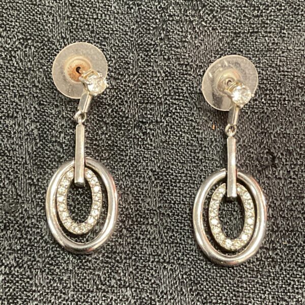 Close-up of silver whitestone stud earrings with sparkling stones.