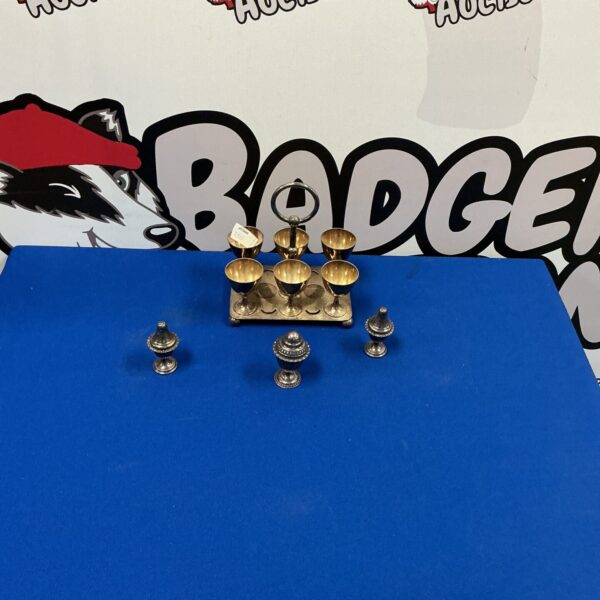 Vintage silverplate egg cups with salt and pepper pots on display.