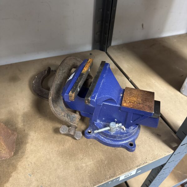 Blue metal bench vice with G clamps for workshop use.