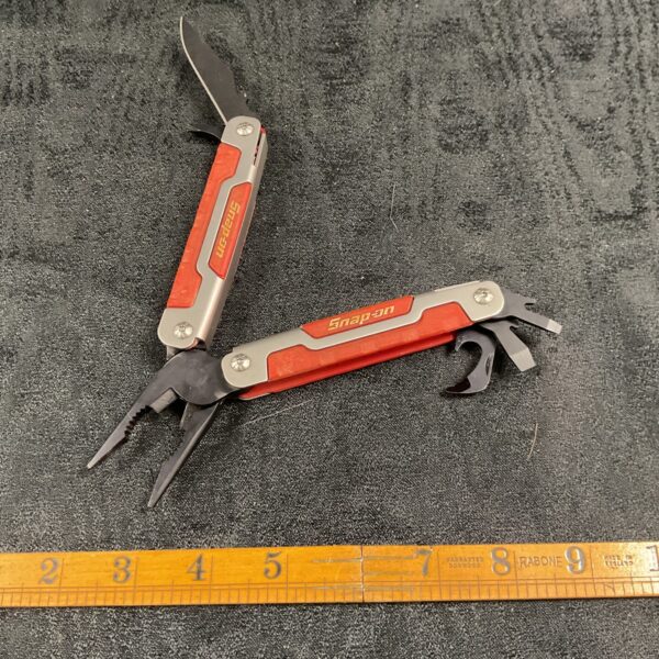 Red and black Snap On multitool with pliers open, showing its functionality.