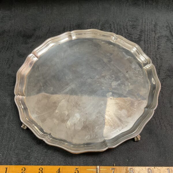 Antique sterling silver tray with decorative rim and ball and claw feet.