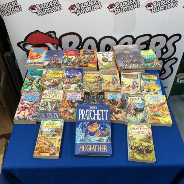 Terry Pratchett novels collection on a table, including signed Hogfather.
