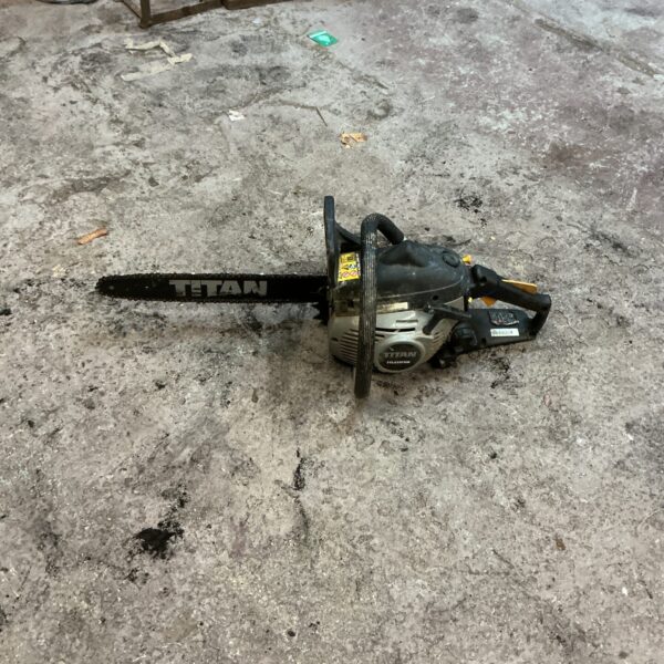 Side view of a used Titan petrol chainsaw for garden work.