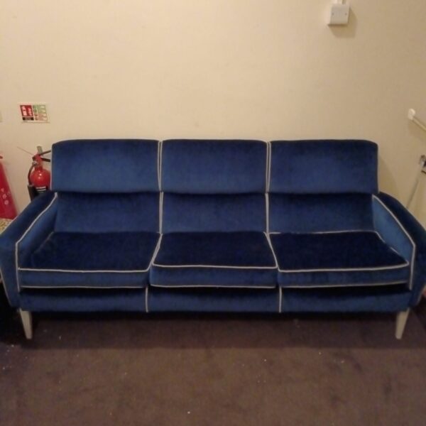 Vintage blue velour three-seater sofa in a living room setting.