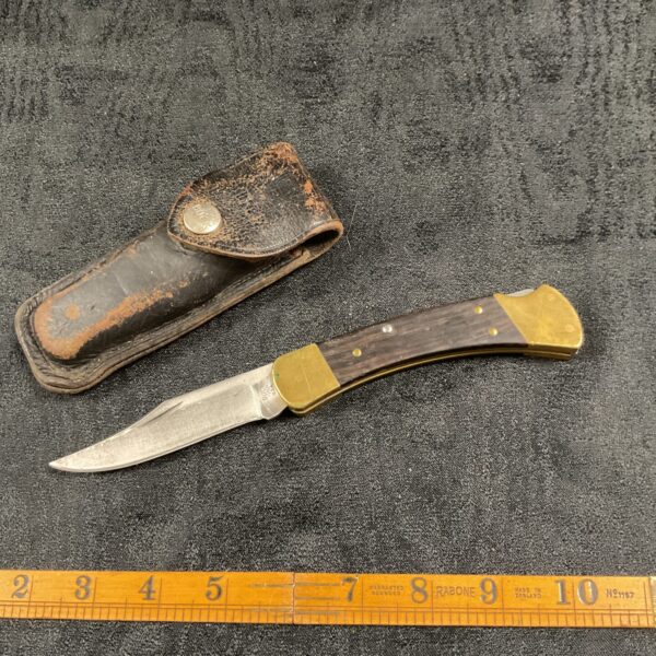 Vintage Buck 110 pocket knife with leather sheath.