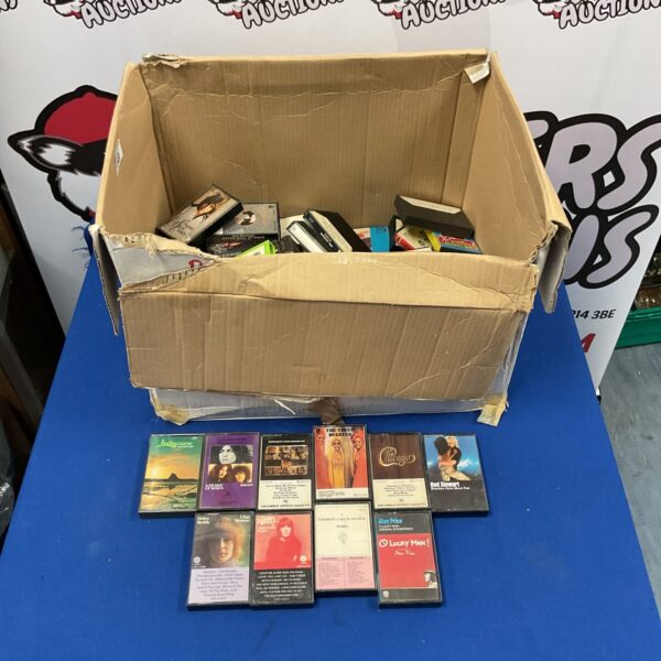 Large lot of vintage cassette tapes in a cardboard box.