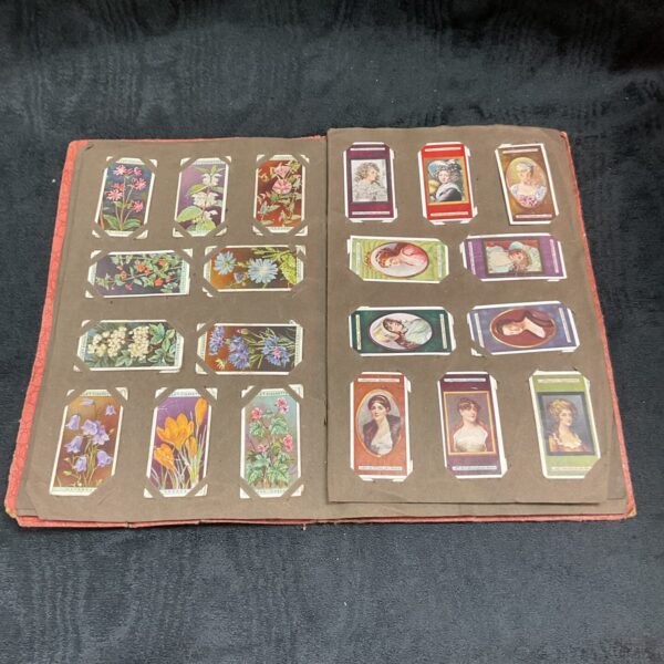 Open vintage cigarette card album showing floral and portrait cards.