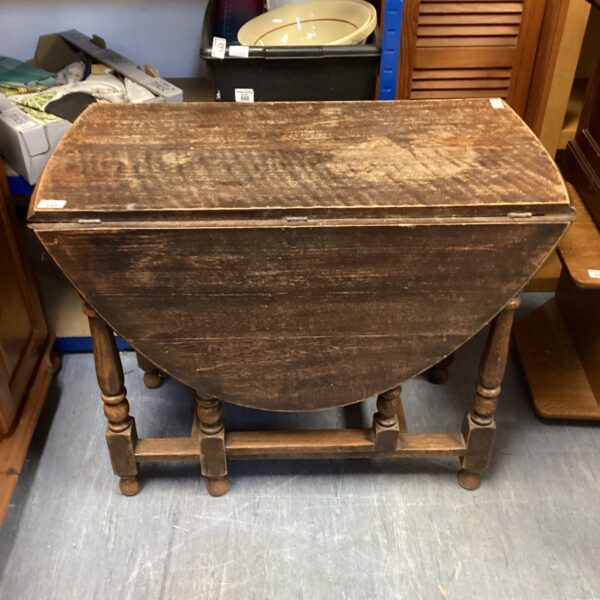 Vintage drop leaf table with wooden top and turned legs.