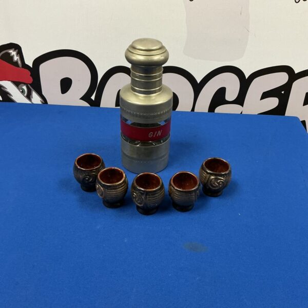 Vintage gin flask set with four matching tumblers on a dark surface.