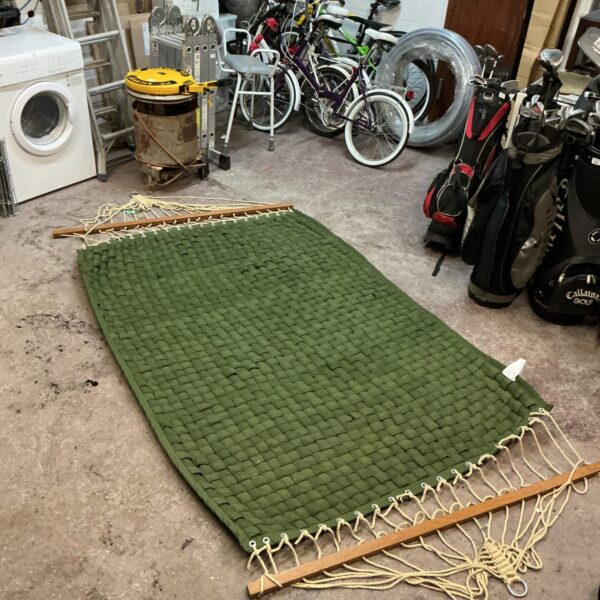Vintage green woven garden hammock with wooden spreaders.