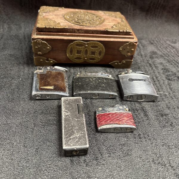 Vintage lighter collection in a decorative wooden box.