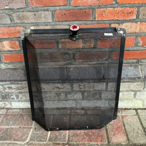 Vintage mesh fire guard with floral handle for fireplace safety.