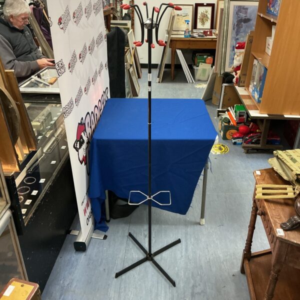 Vintage metal coat and hat stand in a hallway setting.