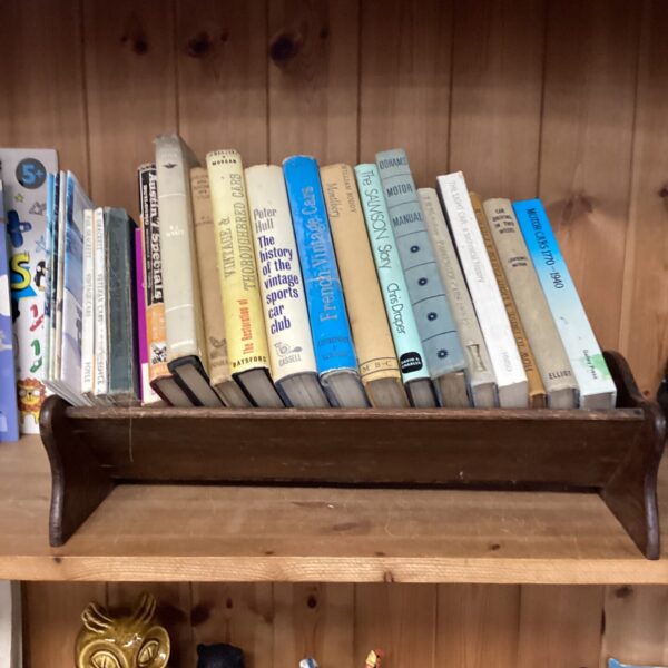 Vintage motoring books on a wooden bookshelf, antique automotive literature.