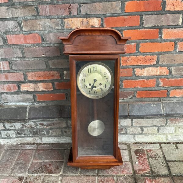 Vintage oak wall clock with pendulum and Roman numeral face.