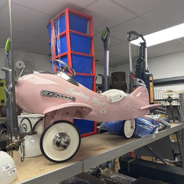 Vintage pink metal pedal car, a collectible ride-on toy.