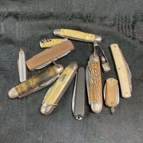 Assorted vintage pocket knives with varied handles and blades.