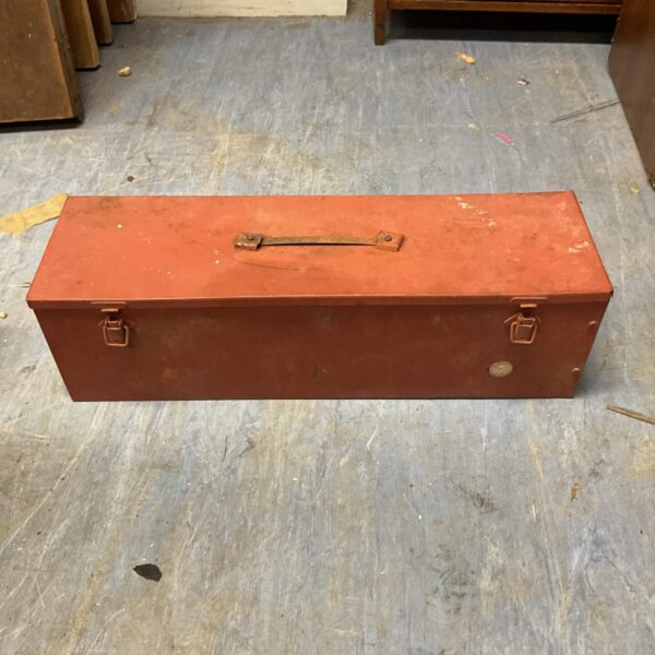 Vintage red metal toolbox with a hinged lid and carrying handle.