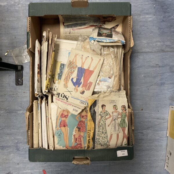 Vintage sewing patterns lot with colourful covers and folded papers.