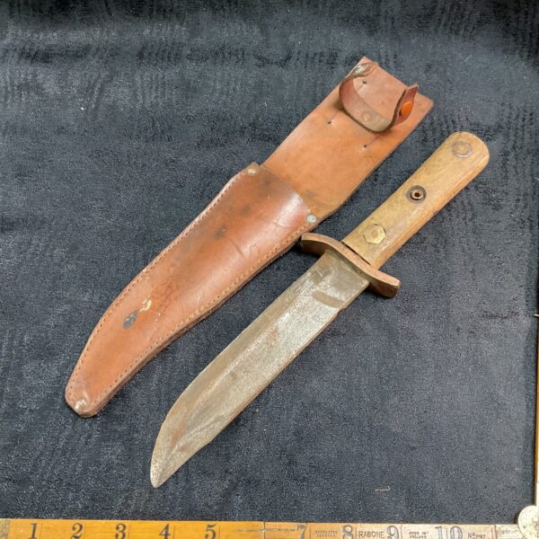 Vintage sheath knife with leather sheath, showing signs of age.