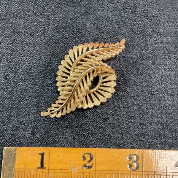 Close-up of vintage Trifari brooch with fern leaf design.