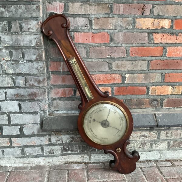 Large vintage wall barometer with ornate wooden frame.