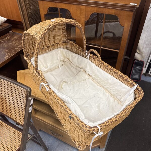 Vintage wicker Moses basket with embroidered lining, a charming nursery item.