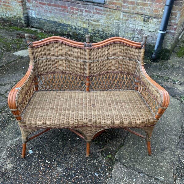 Vintage wicker settee in a garden setting.