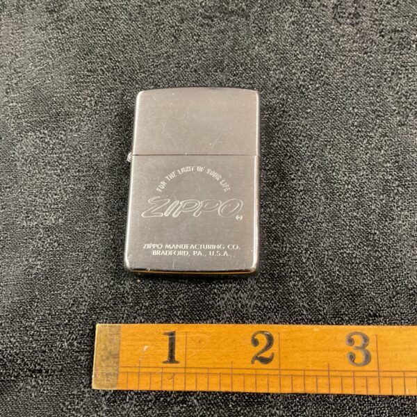 Vintage Zippo lighter with engraved design and branding.
