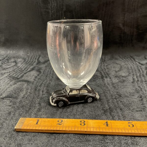 Black VW Beetle base supporting a clear glass.