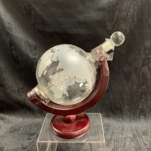 Detailed map on a globe whiskey decanter with wooden base.